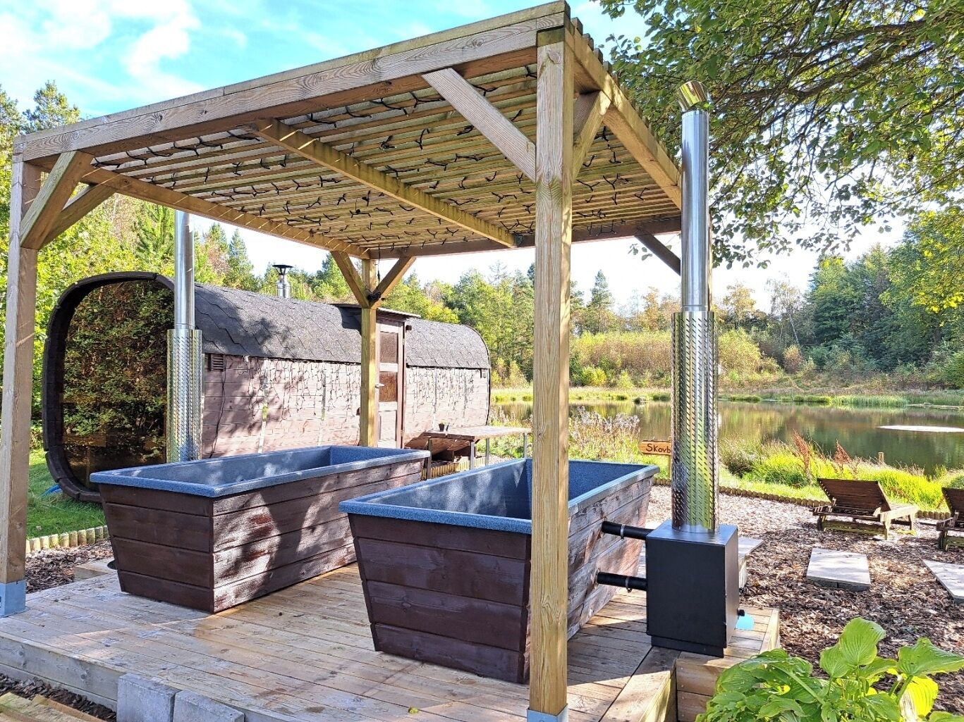 An outdoor barbecue area with stone-built barbecue grills and a wooden pergola.
