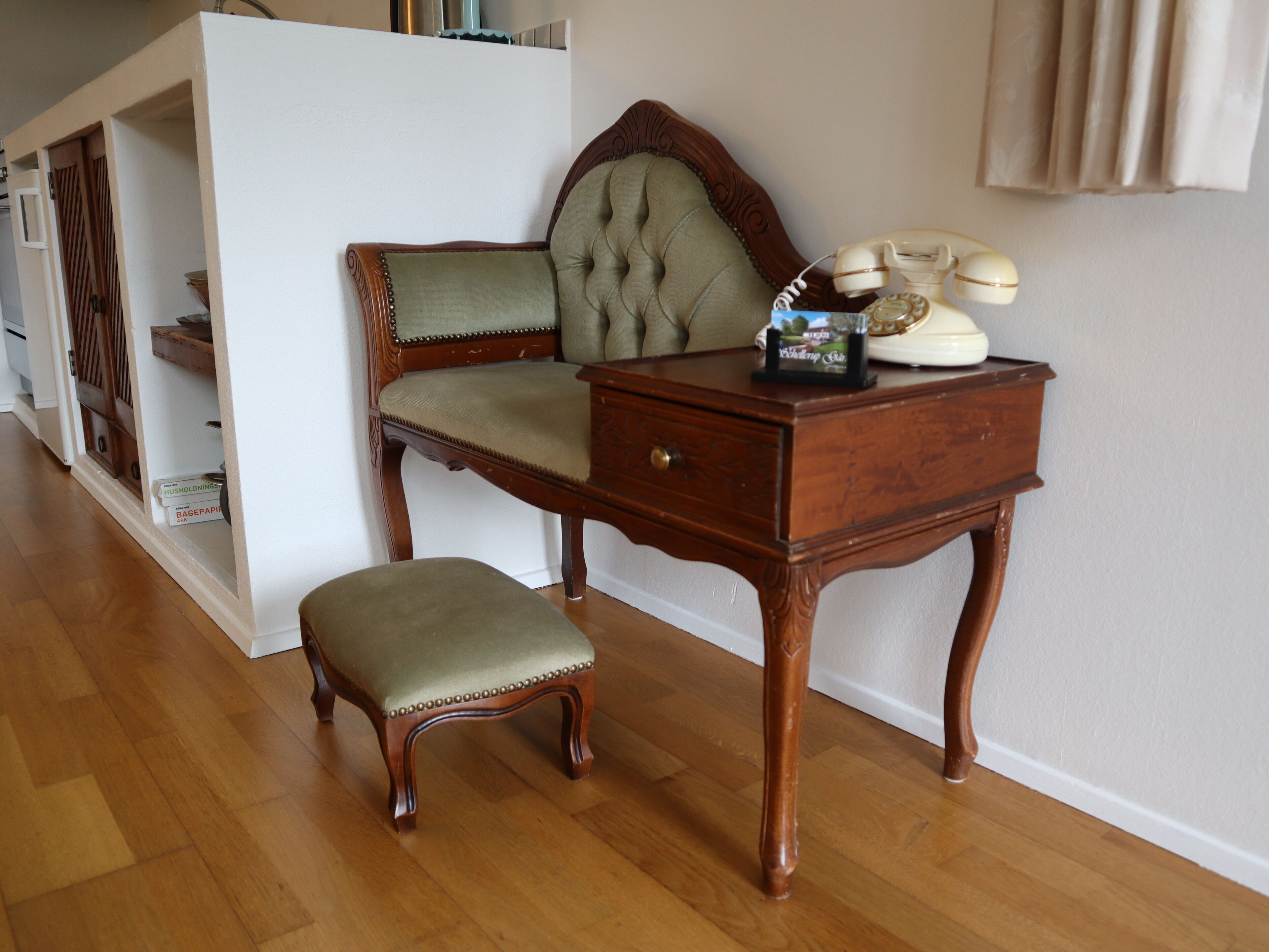 Una habitación con un escritorio de madera, un banco acolchado y un teléfono antiguo.