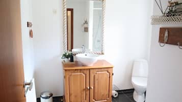 A bathroom with a wooden vanity, white sink, and mirror.