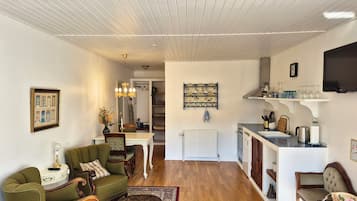 A cozy living room with a fireplace, a dining area with a white table, and a kitchen with modern appliances.