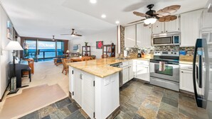 Una cocina amplia con armarios blancos, una isla central y vistas al exterior.