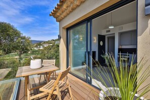 A balcony with a table and chairs, a potted plant, and a view of the surrounding landscape.