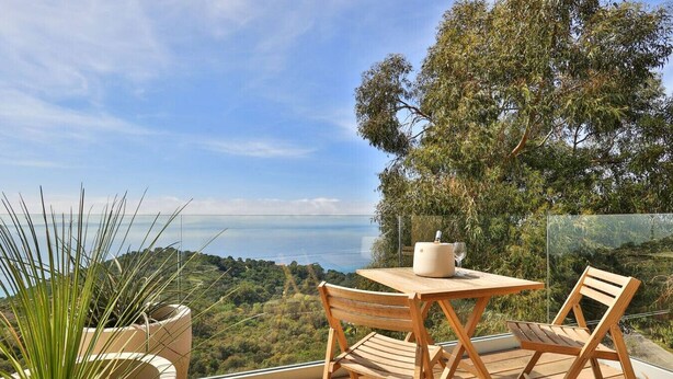 A wooden deck with a table and chairs, overlooking a coastal landscape. - 2-room apartment panoramic sea view (Rayol-Canadel-sur-Mer)