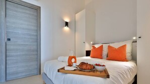 A modern bedroom with a bed, a tray with breakfast items, and a door. - 2-room apartment panoramic sea view (Rayol-Canadel-sur-Mer)