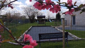 A fenced outdoor area with a bench, a small shelter, and a playground.