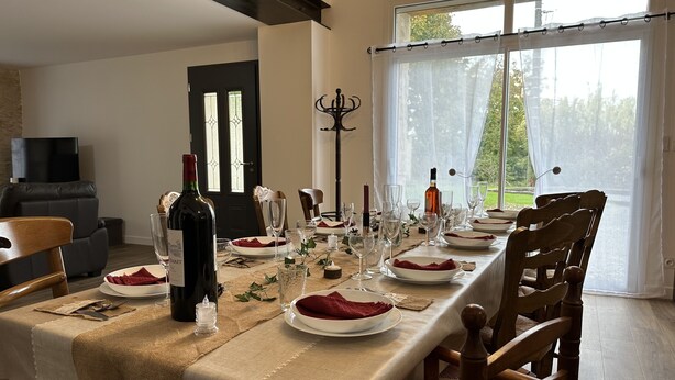 A dining table set for a meal with wine, glasses, and plates.