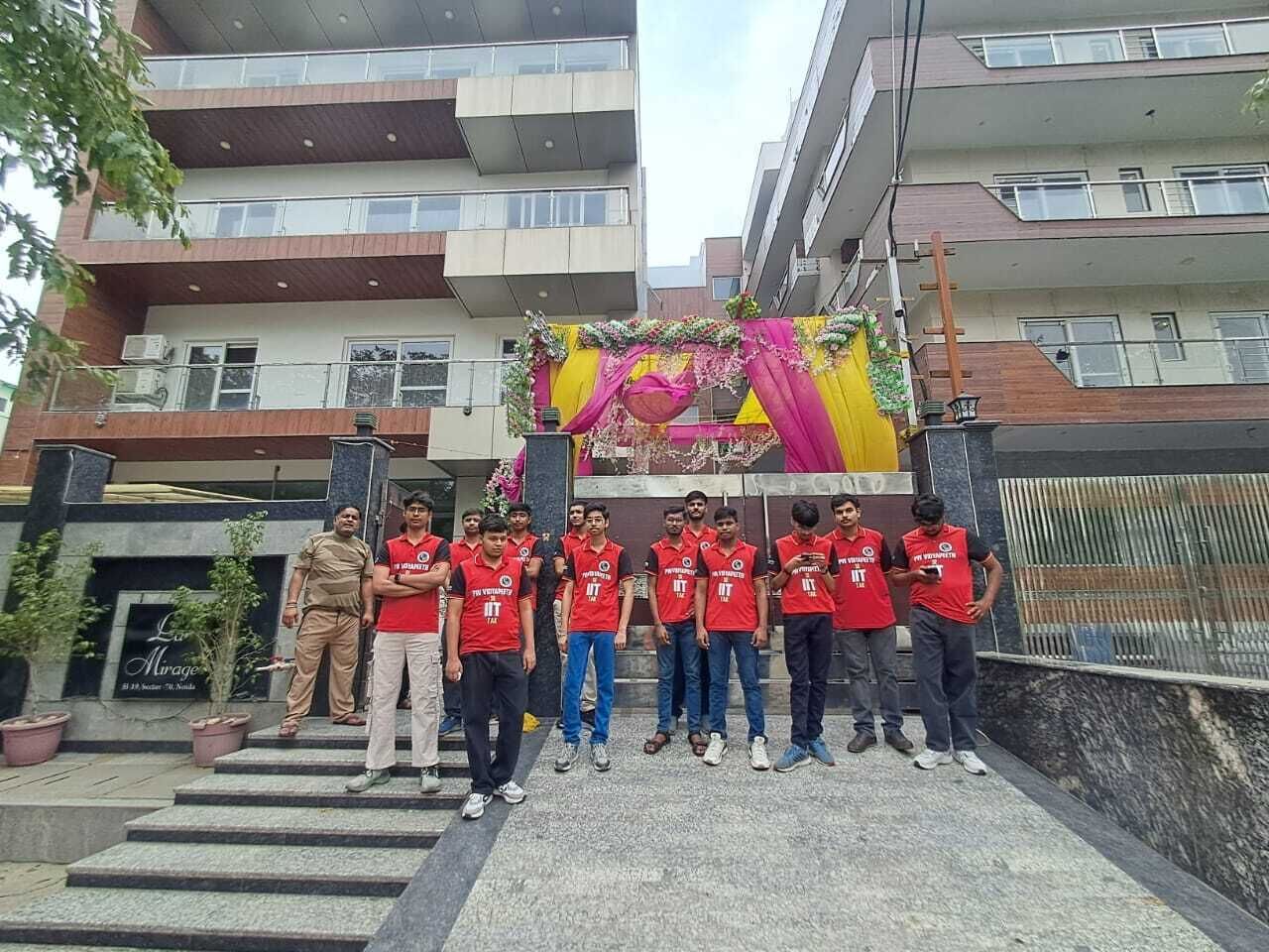 Un grupo de personas de pie frente a un edificio con una escalera que sube a una puerta.
