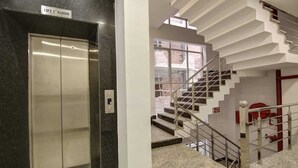 An elevator and a staircase with a red fire extinguisher. - Hotel La Mirage (Noida)
