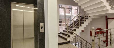 An elevator and a staircase with a red fire extinguisher.