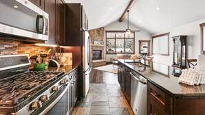A modern kitchen with dark wood cabinets, a stainless steel stove, and a stone backsplash. - Luxury Townhome with Mountain Views, Private Balcony and Walk Out Patio (Keystone)