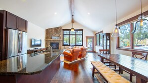 A modern kitchen with a large island, wooden dining table, and built-in seating. - Luxury Townhome with Mountain Views, Private Balcony and Walk Out Patio (Keystone)
