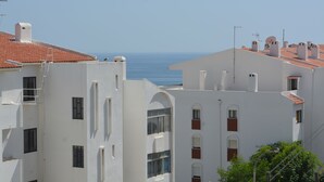 Un bâtiment situé sur la côte, avec des façades blanches et des toits recouverts de tuiles rouges, doté de nombreuses fenêtres et de balcons.