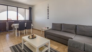 Un salon moderne avec un canapé gris, une table basse blanche et un coin repas comprenant une table et des chaises.