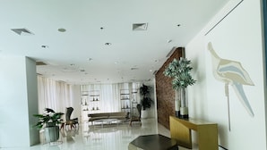 Eine geräumige Lobby mit modernem Design, inklusive einer Sitzecke mit einer Couch und Sesseln, einem Couchtisch und einer Zierpflanze.