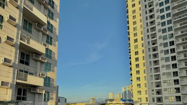Ein Hochhaus mit mehreren Balkonen, großen Fenstern und blauem Himmel.