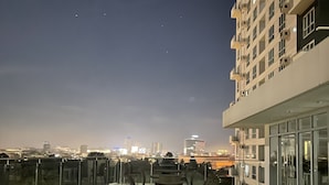 Eine Dachterrasse mit Sitzgelegenheiten und Blick auf die nächtliche Stadtlandschaft.