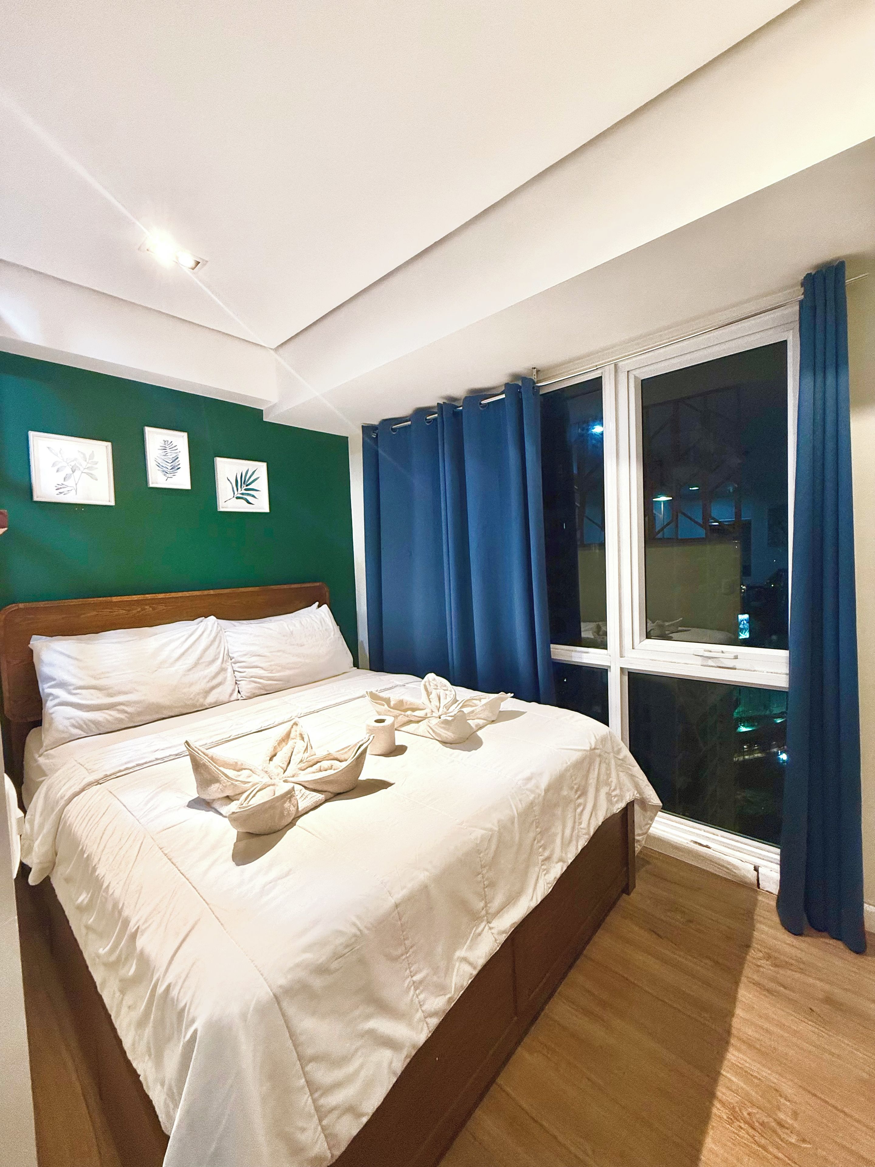 Habitació d'hotel amb un llit, una finestra amb cortines i una obra d'art a la paret.