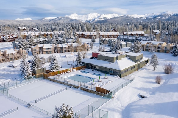 A resort with multiple buildings, a swimming pool, and snow-covered surroundings.