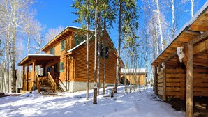 Hirsimökki, jossa on kuisti ja portaat, jotka johtavat sisäänkäynnille.