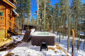 En træhytte med jacuzzi og skitrekk i en snøskov.