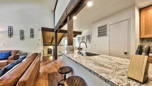 A kitchen with a granite countertop, wooden stools, and a bar area.