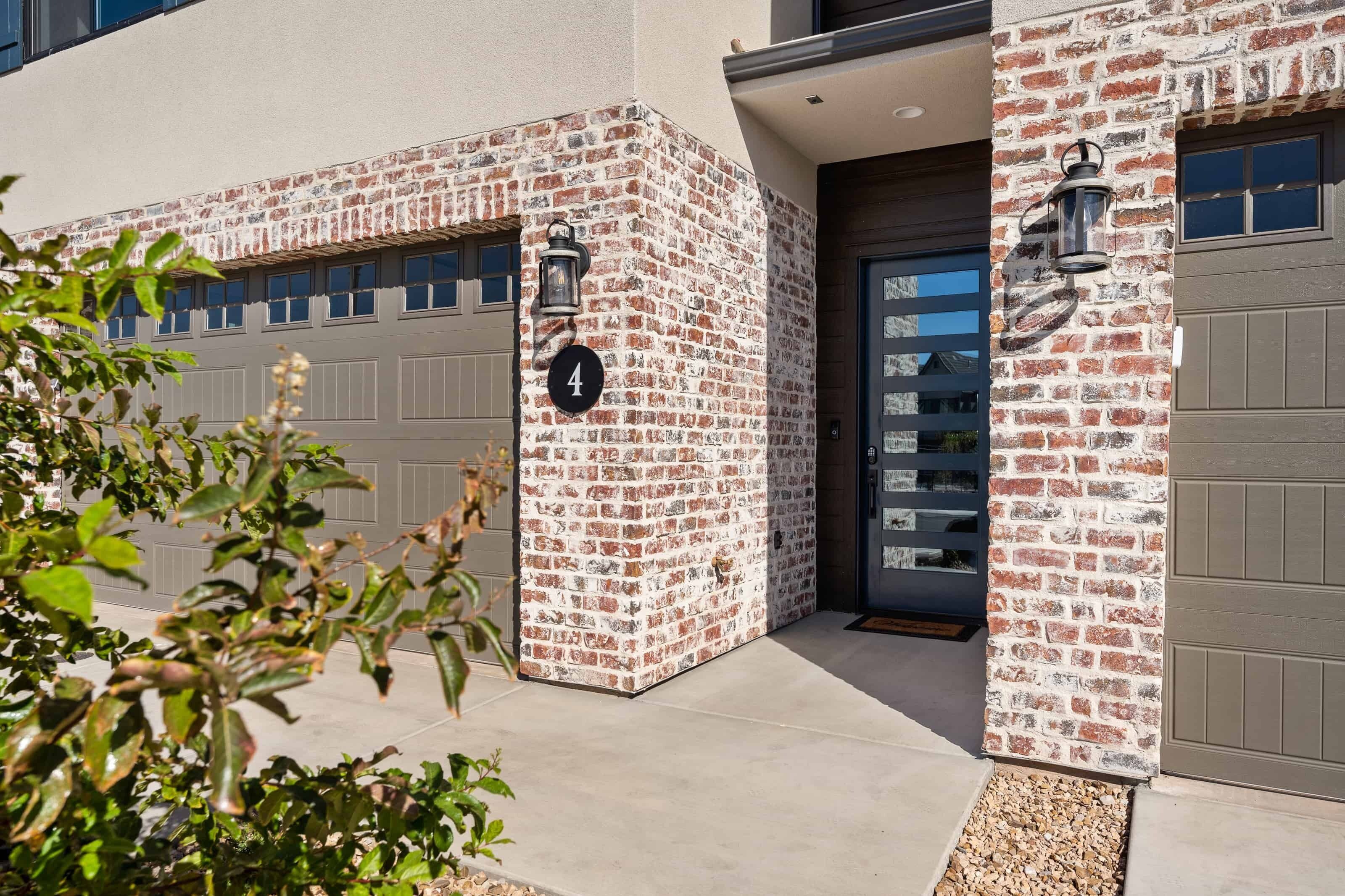 A modern building with a brick facade, numbered 4, and two garage doors.