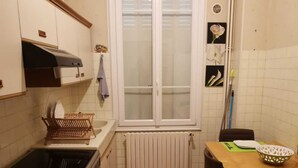 Una cocina compacta con estufa, horno y ventana con persianas.