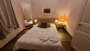 Una habitación de hotel con una cama, una mesita de noche con lámpara, un espejo y una puerta.