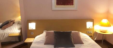 A hotel room with a large bed, two bedside tables, and a nightstand.