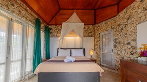 Camera da letto con parete in pietra, un letto a baldacchino, un comodino e un comò.