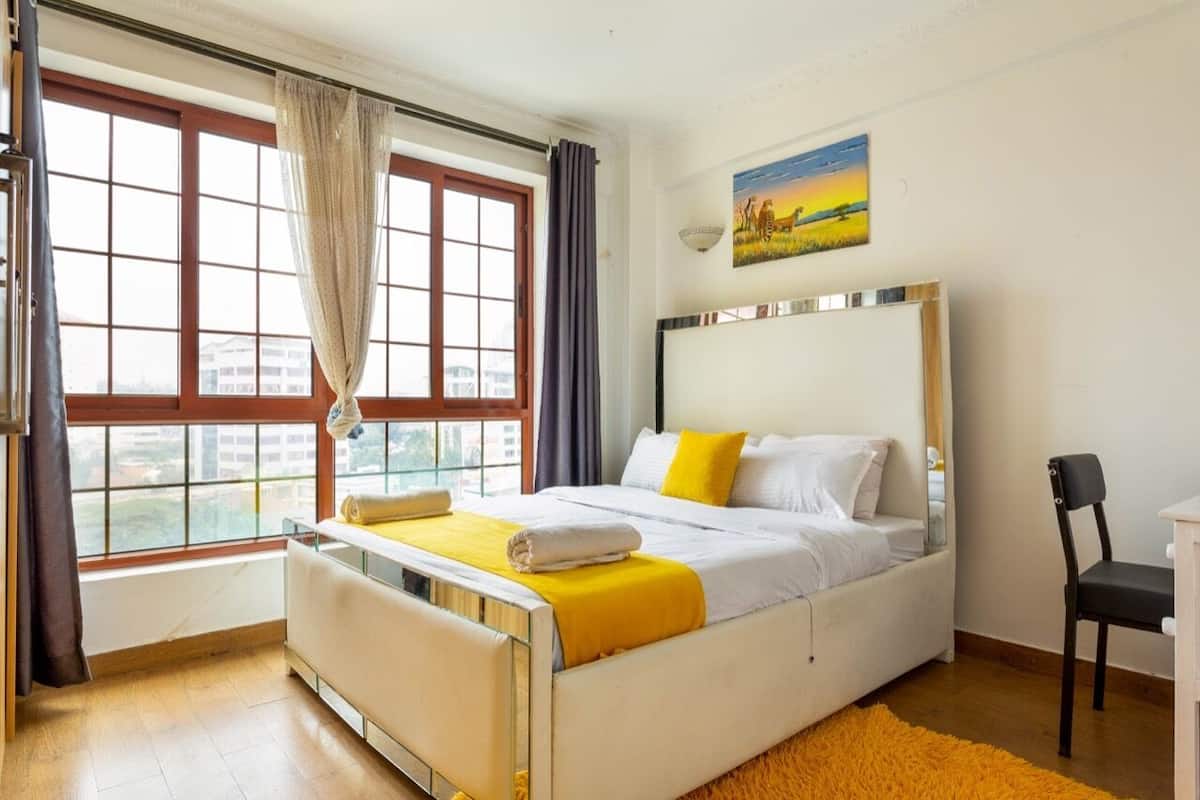 A bedroom with a bed, a chair, a desk, and a window with curtains.