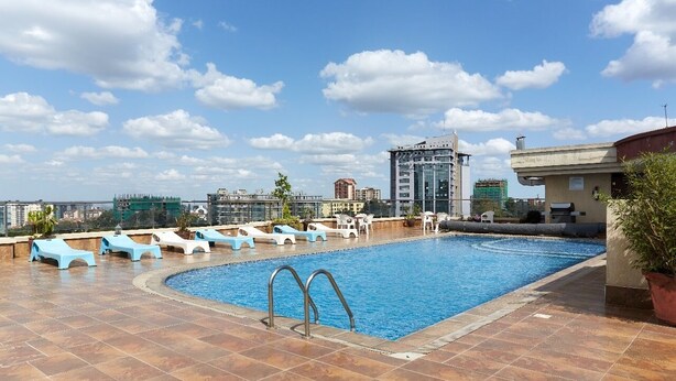 A rooftop swimming pool with lounge chairs and a view of the cityscape.