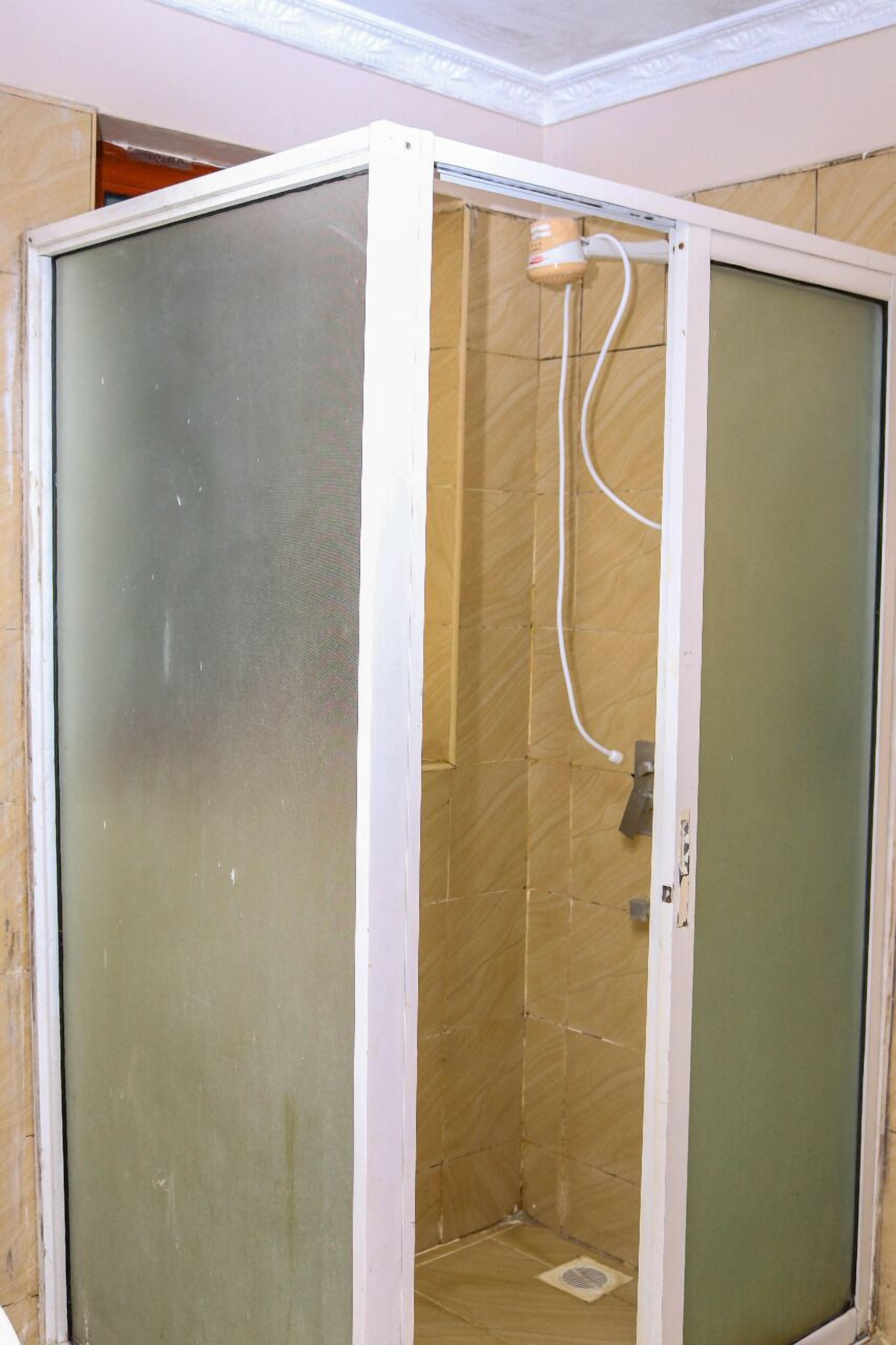 A small, enclosed shower area with a frosted glass door and a showerhead mounted on the wall.