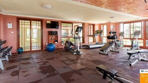 A gym with various exercise equipment, a blue exercise ball, and a television on the wall.