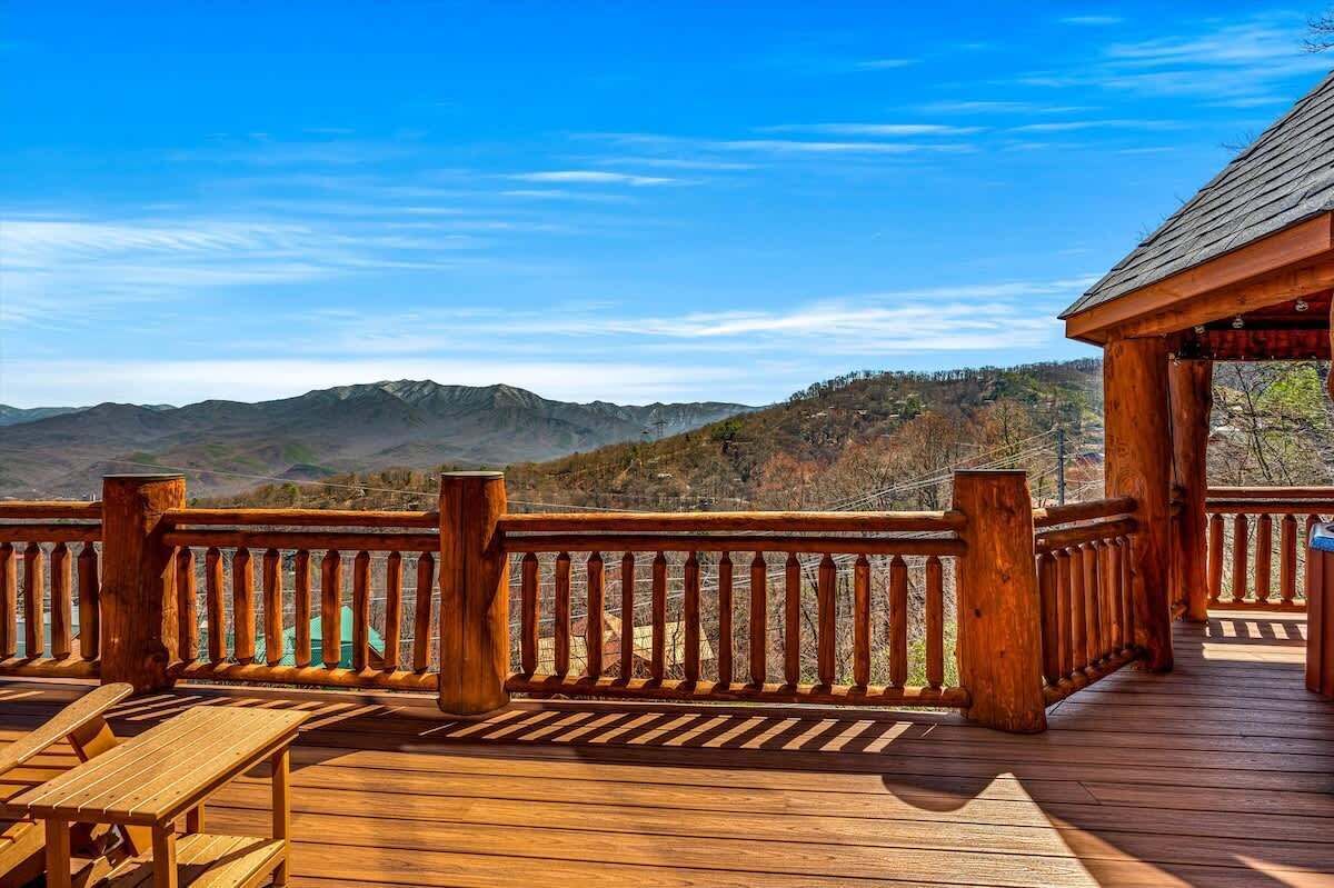 A wooden deck with a railing, overlooking a mountainous landscape.