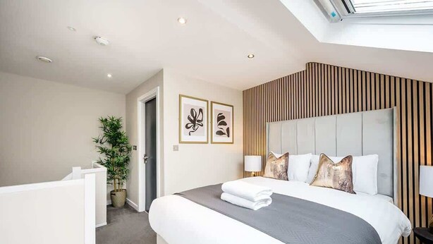 A modern hotel room with a large bed, a potted plant, and a view of the sky through a skylight. - Host & Stay | Halifax House Living (Liverpool)