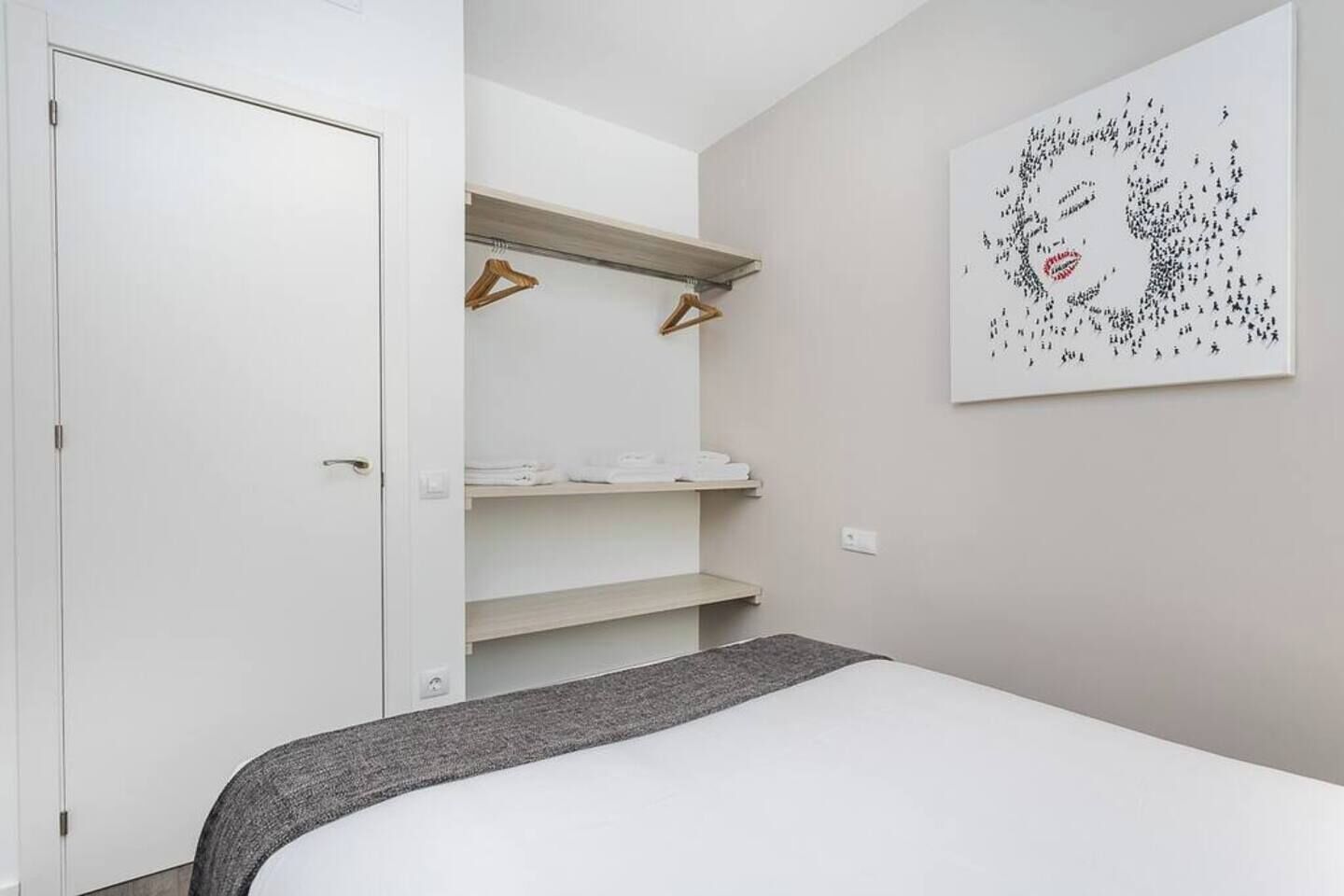 A bedroom with a bed, a wardrobe, and a wall-mounted artwork.