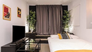 Ein modernes Hotelzimmer mit einem Bett, einem Fernseher, einem Schreibtisch und zwei Blumentöpfen.