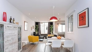 Ein modernes Wohnzimmer mit Essbereich, Küche und einem großen Fenster.