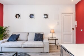 Een woonkamer met een bank, een lamp en drie ronde objecten in lijsten aan de muur.