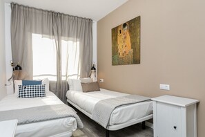 Une chambre d’hôtel avec deux lits, une table de chevet, une lampe et un tableau au mur.