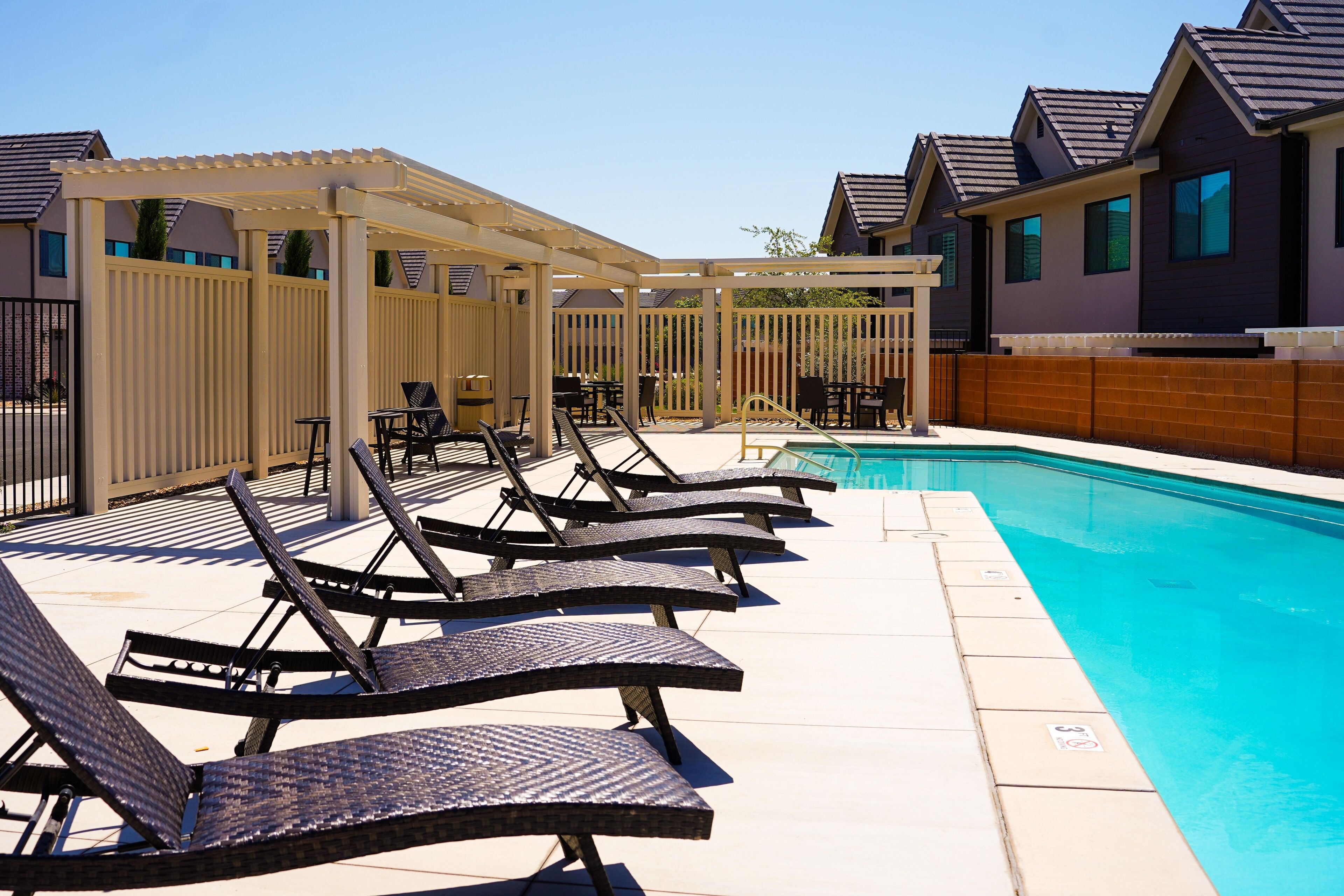 A poolside area with lounge chairs and a covered seating area.