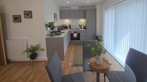 A modern apartment with a kitchen, dining area, and a large window. - Snuggle Inn - Riverside apartment- Woolwich Ferry, Mins to O2 Arena (Woolwich)