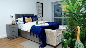 A bedroom with a bed, bedside table, and a chair. - Snuggle Inn - Riverside apartment- Woolwich Ferry, Mins to O2 Arena (Woolwich)