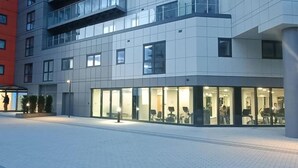 A modern building with a glass facade, a covered outdoor area, and a paved walkway. - Snuggle Inn - Riverside apartment- Woolwich Ferry, Mins to O2 Arena (Woolwich)