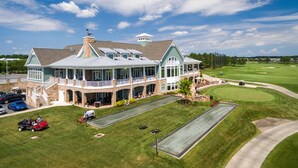 A large building with multiple levels, a covered patio, and a well-maintained lawn with a putting green. - Three bedroom condominium in the Windswept community at The Peninsula! (Millsboro)