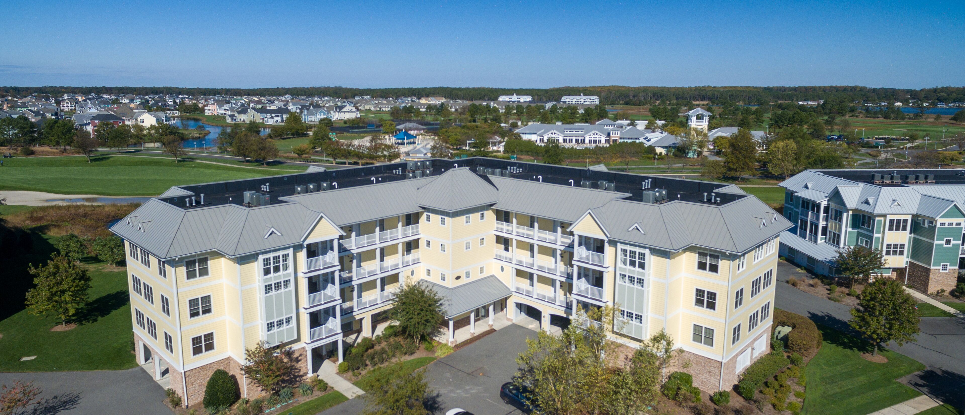 A multi-story hotel with a central courtyard, surrounded by a golf course and residential area.