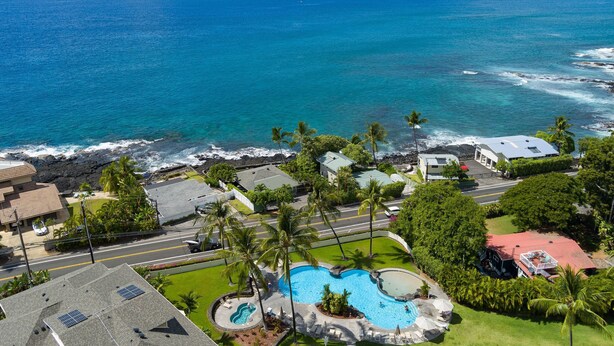 A residential area with a swimming pool, houses, and a view of the ocean.