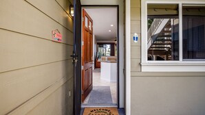 A house entrance with a wooden door, a welcome mat, and a staircase leading to an upper level.