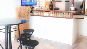 A kitchen with a bar area, a dining table, and a television mounted on the wall.